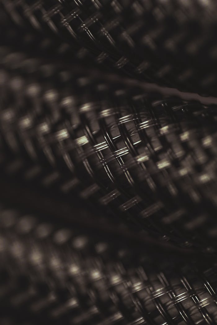 Detailed close-up of a dark, braided metal wire texture showcasing intricate patterns.